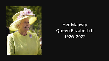 A medium-shot picture of Her Majesty the Queen wearing a primrose yellow coat with a brooch on the left shoulder and a matching hat with pink flowers on the brim. She is looking to the right and smiling. The picture is on a black background. In white are the words Her Majesty Queen Elizabeth II 1926–2022.